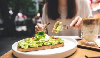 Tips for Weight Loss Without Exercise woman-cutting-avocado-toast-outdoor-restaurant