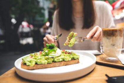 Tips for Weight Loss Without Exercise woman-cutting-avocado-toast-outdoor-restaurant
