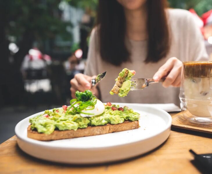 Tips for Weight Loss Without Exercise woman-cutting-avocado-toast-outdoor-restaurant