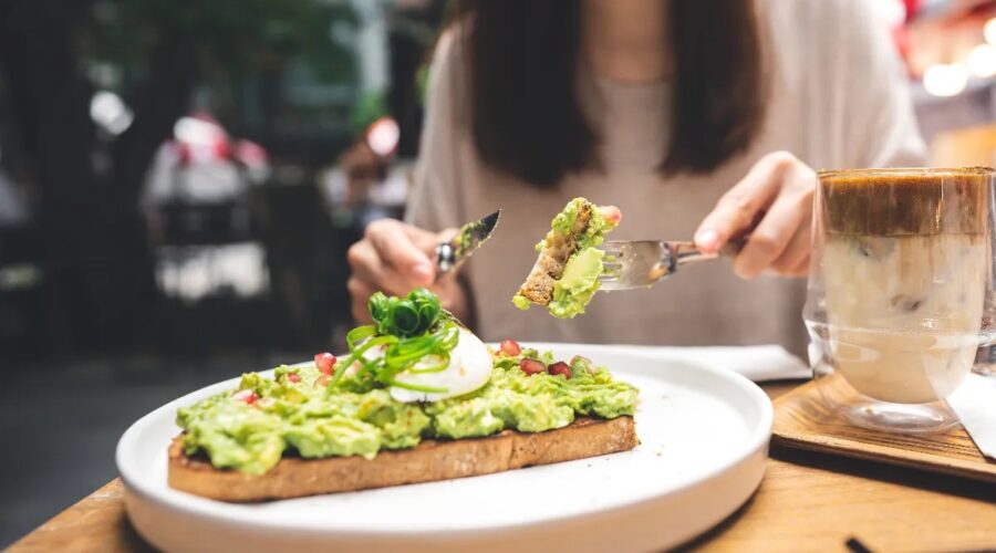 Tips for Weight Loss Without Exercise woman-cutting-avocado-toast-outdoor-restaurant