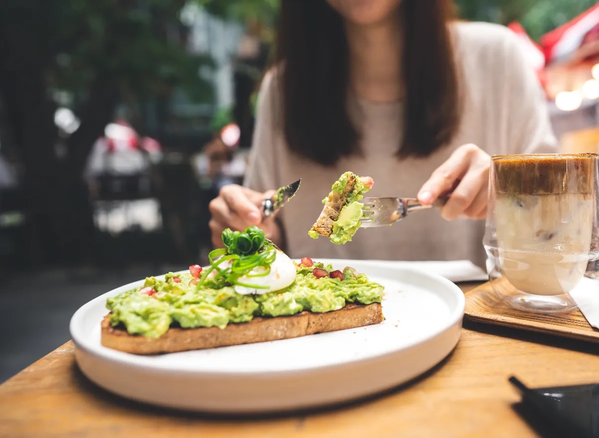 Tips for Weight Loss Without Exercise woman-cutting-avocado-toast-outdoor-restaurant